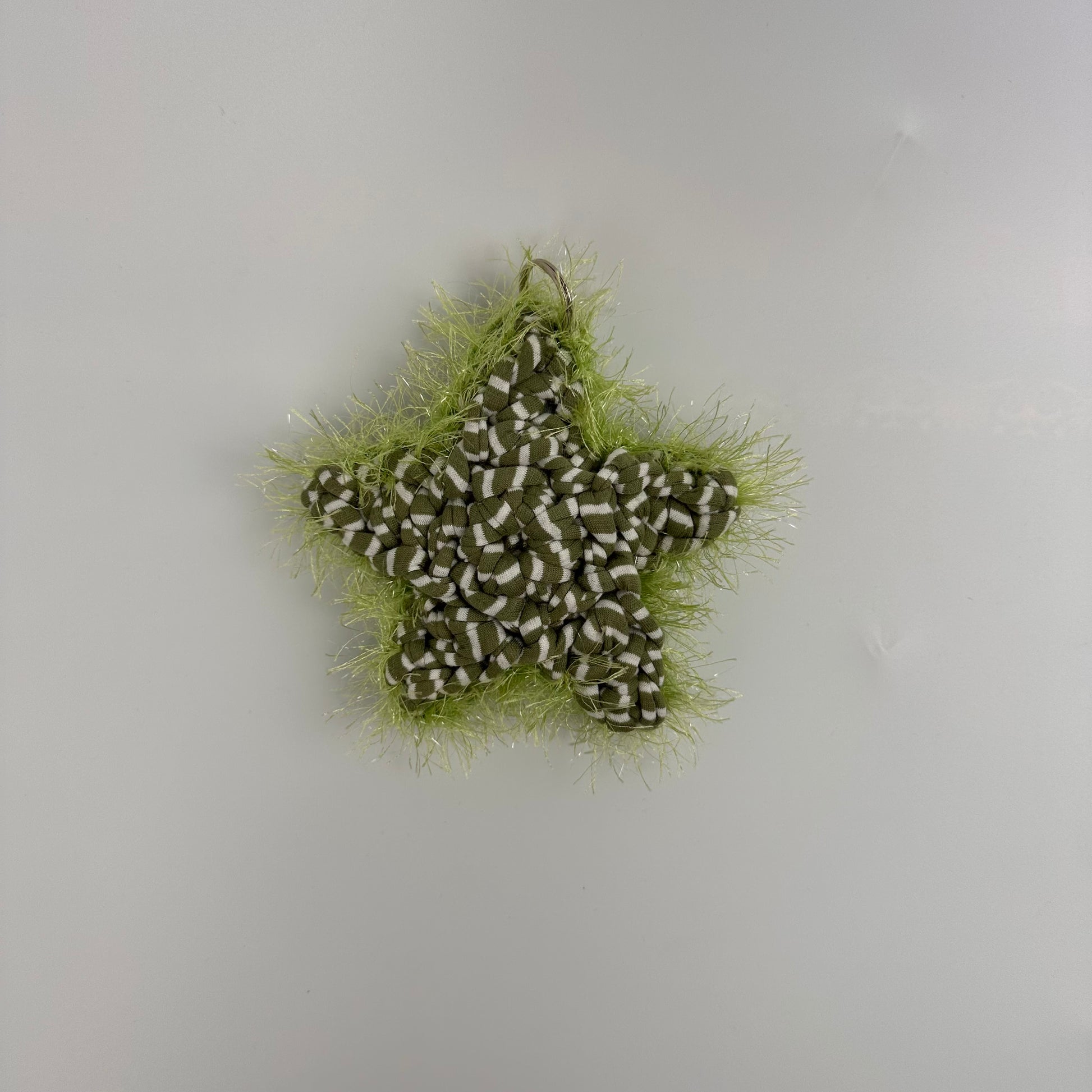 Star-shaped bag accessory with lime green tinsel on a light grey background