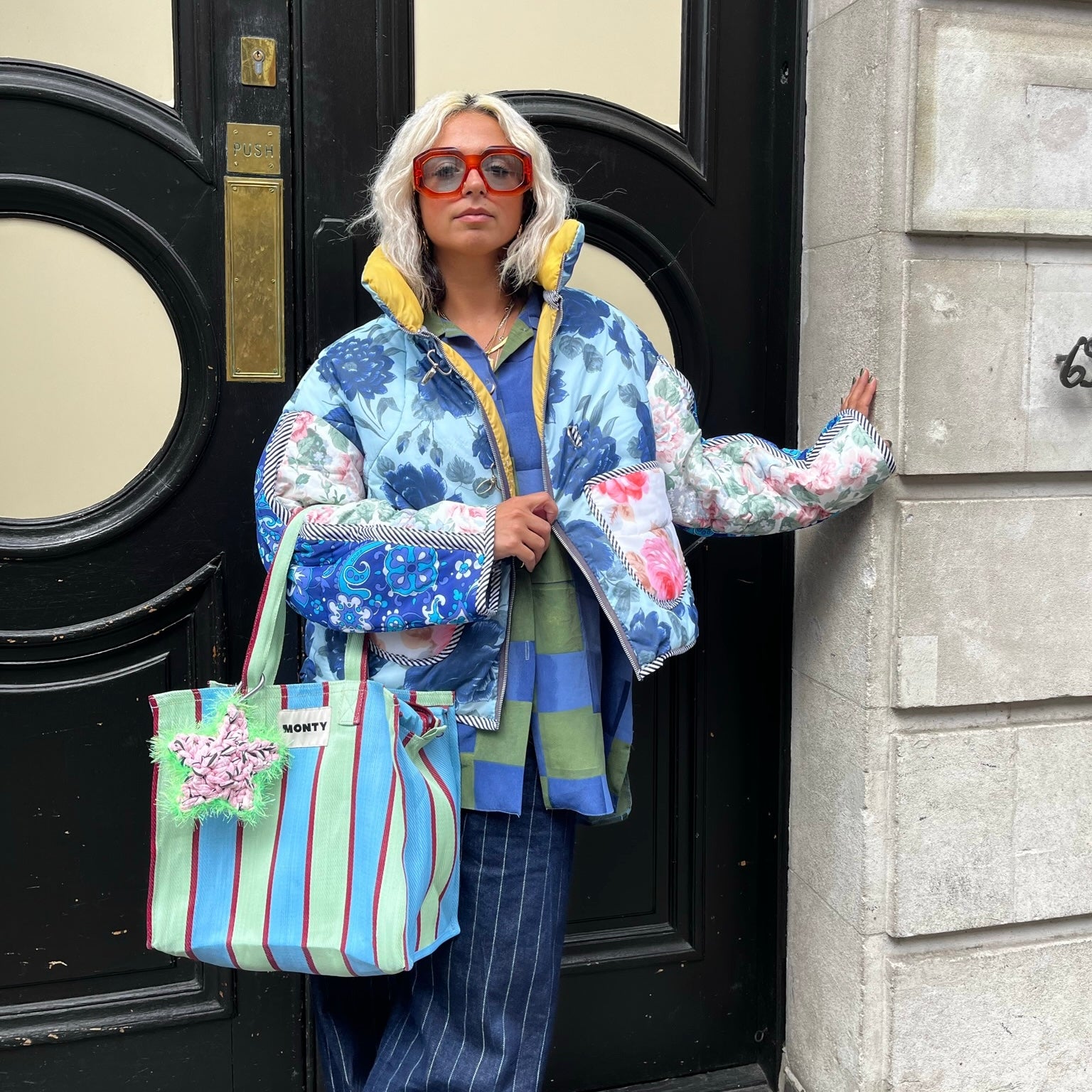 Model in a doorway, wearing a colourful outfit with a Sloe Mosey Star Bag charm